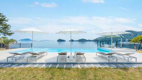 a pool with chairs and umbrellas and the water at namhae sea stay N pet pension in Namhae