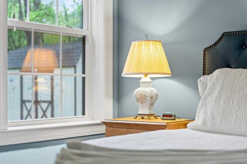 a bed with a lamp on a night stand next to a window at Chalet on Chalet by AvantStay Bright Cabin w Deck Fire Pit Near Lake in Lake Harmony
