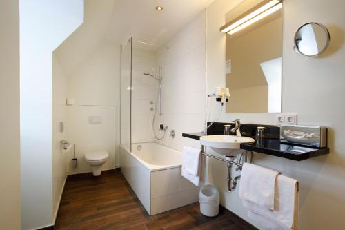 uma casa de banho com um lavatório, um WC e um espelho. em Hotel am Jakobsmarkt em Nuremberga