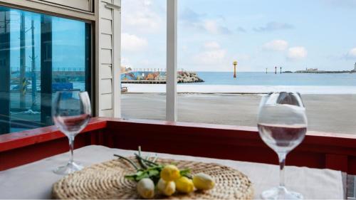 two wine glasses on a table with a view of the ocean at Goseong Badasga per Osyeonbyu Pension in Goseong