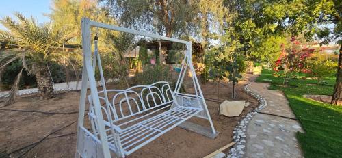 a white swing in a garden with trees at NMY Farm1 in Ras al Khaimah