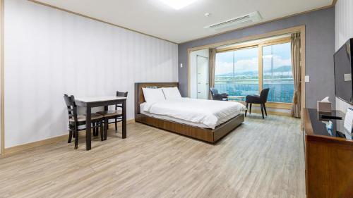 a bedroom with a bed and a desk and a table at Jeju Badagreen Pension in Jeju
