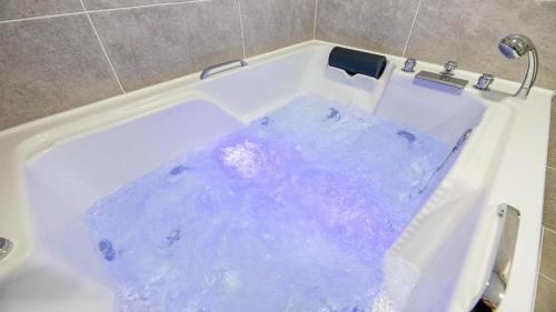 eine Badewanne mit blauem Wasser und einem Wasserhahn in der Unterkunft Gapyeong Haneulsup Spa Pension in Gapyeong
