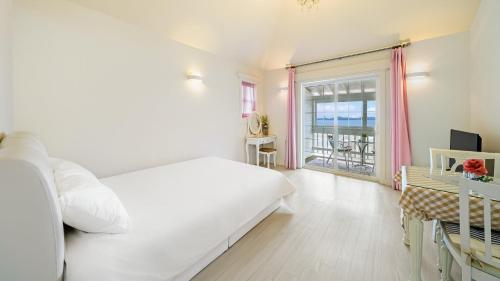 a white bedroom with a large bed and a desk at Ganghwa Daeun pension in Incheon