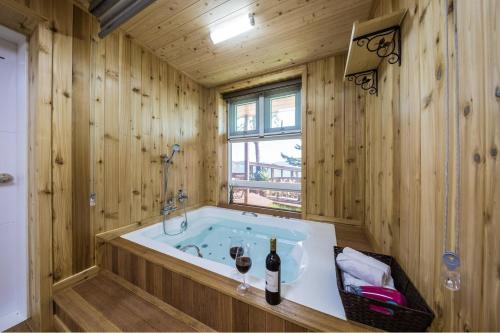 a wooden bathroom with a tub with two glasses of wine at Tongyoung S468 Poolvilla in Tongyeong