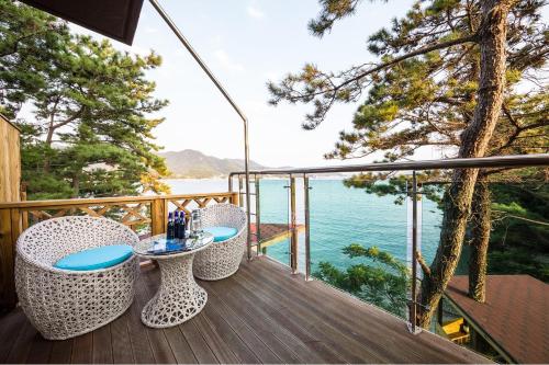 a balcony with a table and chairs on a deck with the water at Tongyoung S468 Poolvilla in Tongyeong