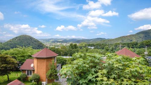 a house with mountains in the background at Paju Sugavill Agyeon dongban Pension in Paju