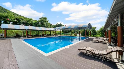 a swimming pool with two benches next to a building at Paju Sugavill Agyeon dongban Pension in Paju