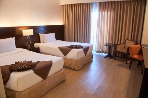 a hotel room with two beds and a table at Harolds Hotel Cebu in Cebu City