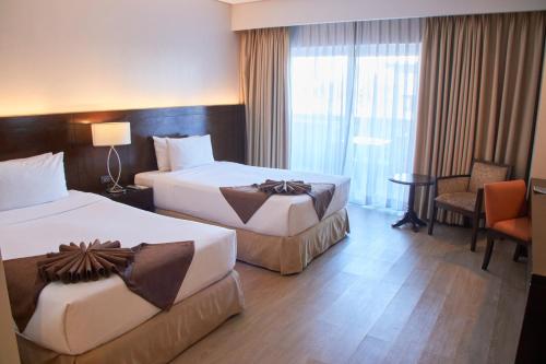 a hotel room with two beds and a table at Harolds Hotel Cebu in Cebu City
