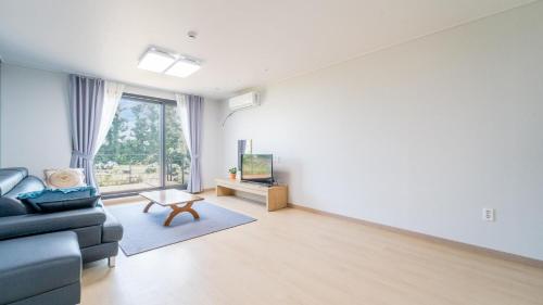 un soggiorno con un divano e una TV di Jeju ChunJaNe Pension a Seogwipo