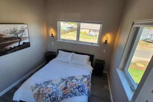 a small bedroom with a bed and two windows at Modern Furnished Retreat in Eugene