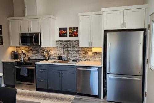 a kitchen with white cabinets and a stainless steel refrigerator at Modern Furnished Retreat in Eugene