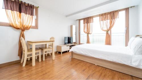a bedroom with a bed and a desk and a television at jeju ondamhouse pension in Jeju