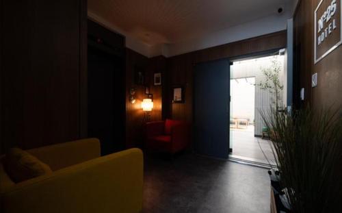 a living room with a couch and a door with a chair at No25 Hotel Naeoe in Gimhae