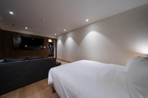 a bedroom with a white bed and a couch at No25 Hotel Naeoe in Gimhae