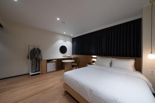 a bedroom with a large white bed and a desk at No25 Hotel Naeoe in Gimhae