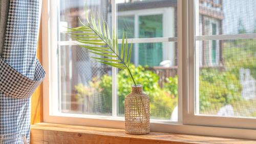 a vase sitting on a window sill with a plant in it at Yeosu Noeul Walk Pet Pension in Yeosu