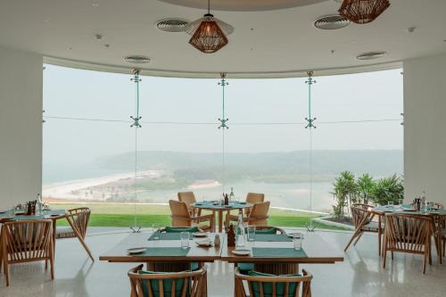a restaurant with tables and chairs and a large window at Araqila Boutique Beach Resort near MOPA airport in Vengurla