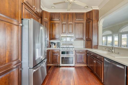 a kitchen with wooden cabinets and a stainless steel refrigerator at Haven by AvantStay Luxury Beachfront Home w Pool Gorgeous Patios in Sullivans Island