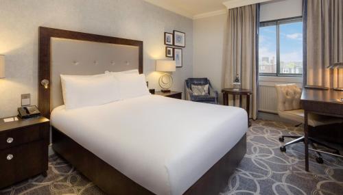 a hotel room with a large bed and a desk at Glasgow Grosvenor Hotel in Glasgow