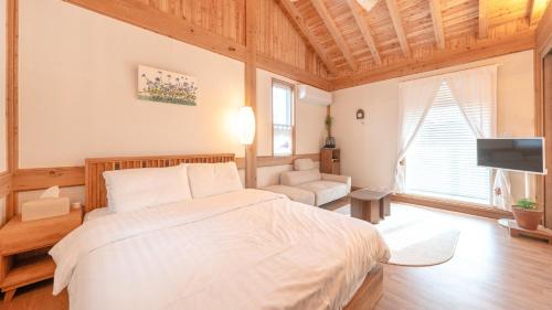a bedroom with a large bed and a television at Gangneung Gangmunsosodam Pension in Gangneung