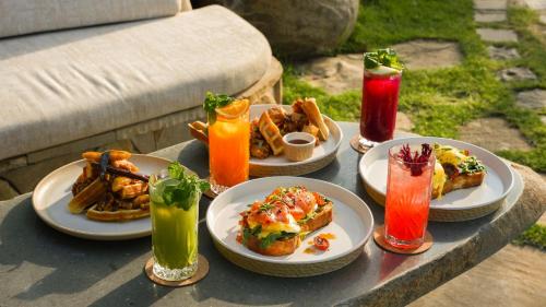 a table with plates of food and drinks on it at Nuanu Suites & Accommodations in Tabanan