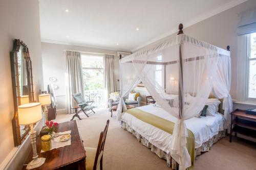 een slaapkamer met een hemelbed en een tafel bij Hacklewood Hill Country House in Port Elizabeth