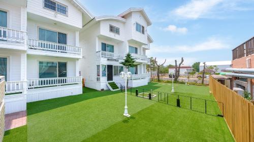 an apartment with a lawn in front of a building at Taean minoseu Pet Pension in Taean