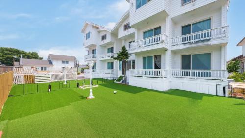 a large white building with a yard with green grass at Taean minoseu Pet Pension in Taean