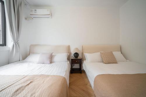 two beds sitting next to each other in a room at Tonight Homestay West Nanjing Road Shanghai in Shanghai