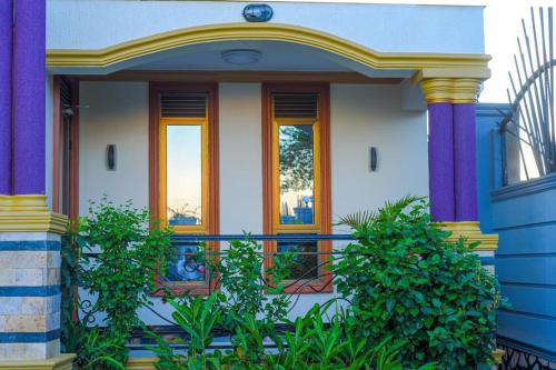 a house with purple columns and a balcony with plants at Gloria Villas in Entebbe