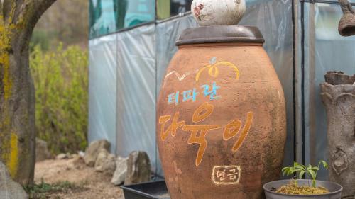 an old vase with writing on it next to a tree at Gapyeong The Paran Private Pool Villa in Gapyeong