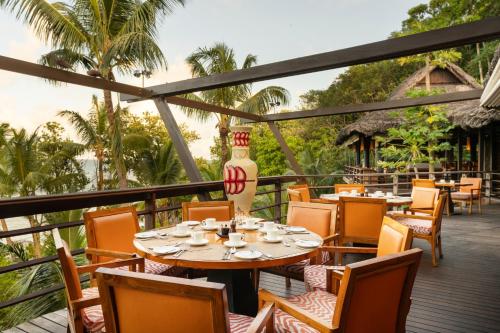 a restaurant with tables and chairs on a deck at Constance Lemuria in Grand'Anse Praslin