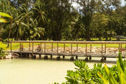 two people riding bikes on a bridge over a river at Constance Lemuria in Grand'Anse Praslin