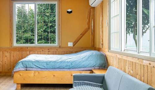 una piccola camera da letto con un letto e due finestre di Jeju Jeonwonsaenghwal Diorem Pension a Jeju