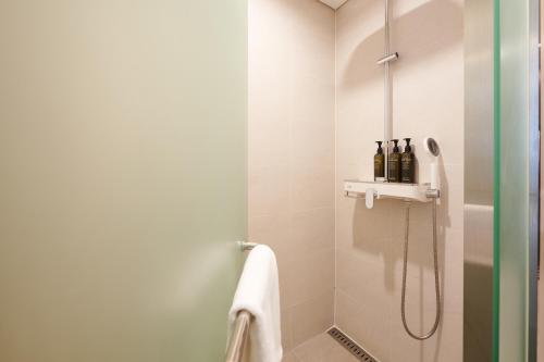 a bathroom with a shower with bottles on a shelf at Nine Tree by Parnas Seoul Dongdaemun in Seoul
