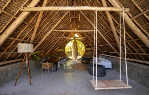 an attic room with a wooden ceiling with a table and chairs at Bamboo Zanzibar in Jambiani