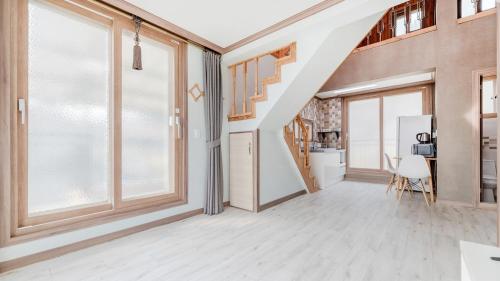 an empty living room with a staircase and large windows at Samcheok Bongsuni-unni Pension in Samcheok