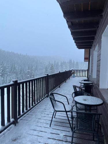 a balcony with tables and chairs and snow covered trees at Мелодія Гір Вид на гори in Vorokhta
