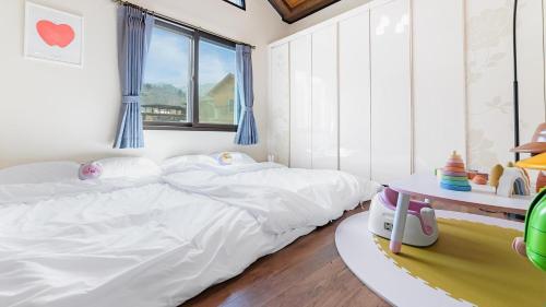 a bedroom with a white bed and a table at Namyangju HAIMOM Family Pension Black in Namyangju