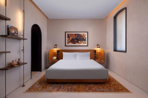 a bedroom with a white bed and two lights at The Chedi Hegra, AlUla in AlUla