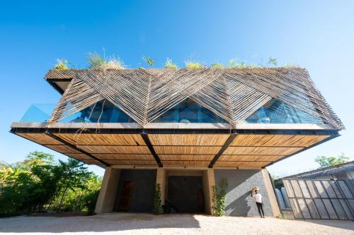 a person standing in front of a building with a roof at Bamboo Zanzibar in Jambiani