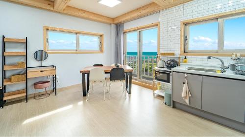 a kitchen with a table and some windows at Jeju Hoyeongfarm Stay in Jeju