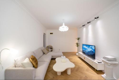 a white living room with a couch and a tv at Tonight Homestay West Nanjing Road Shanghai in Shanghai
