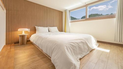 a bedroom with a large white bed with a window at Chuncheon Lio Pension in Chuncheon