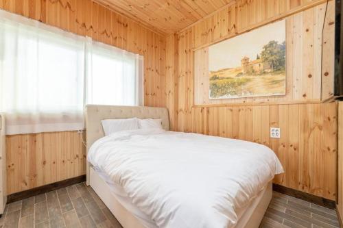 a bedroom with a bed in a wooden room at Seogwipo Unyeong Pension in Seogwipo
