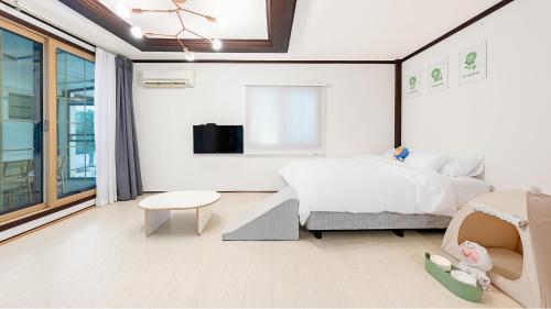 a white bedroom with a bed and a table at Pocheon luxjay pet Pension in Pocheon