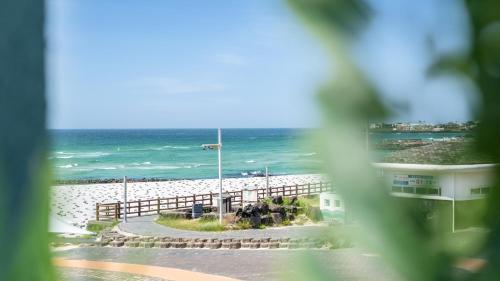 a view of a beach from a window with the ocean at jeju aeworio pension in Jeju