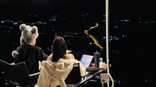 two people sitting in chairs looking at the city at night at Peace Zone เขาค้อ in Khao Kho
